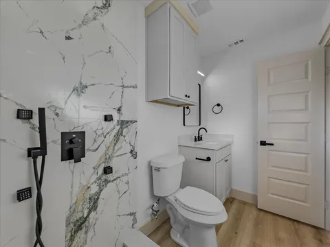 Remodeled bathroom shower area with marble tile and black fixtures